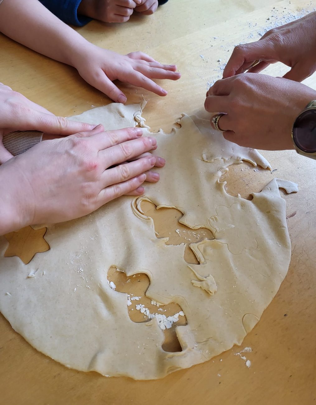 Hands of different sizes pressing into cookie dough