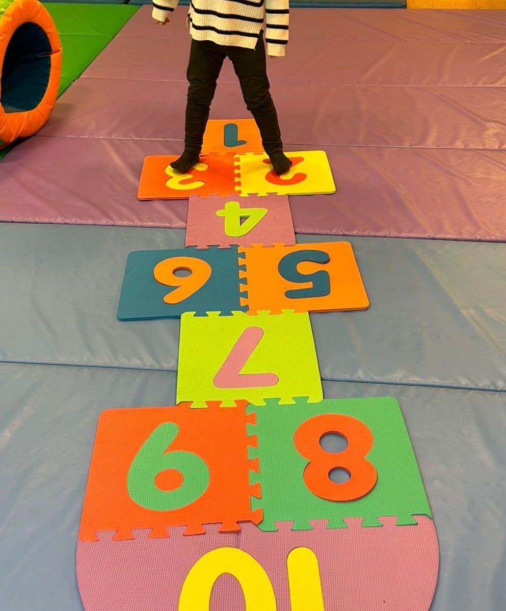 A child stepping along a colourful number hopscotch trail