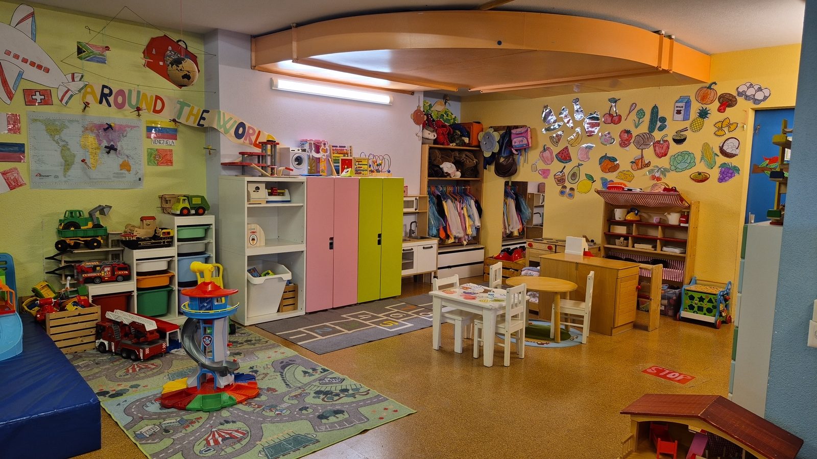 Cogmo Kids classroom with an 'Around the World' theme — pretend kitchen, dress-up corner, hopscotch rug and shelves of toys